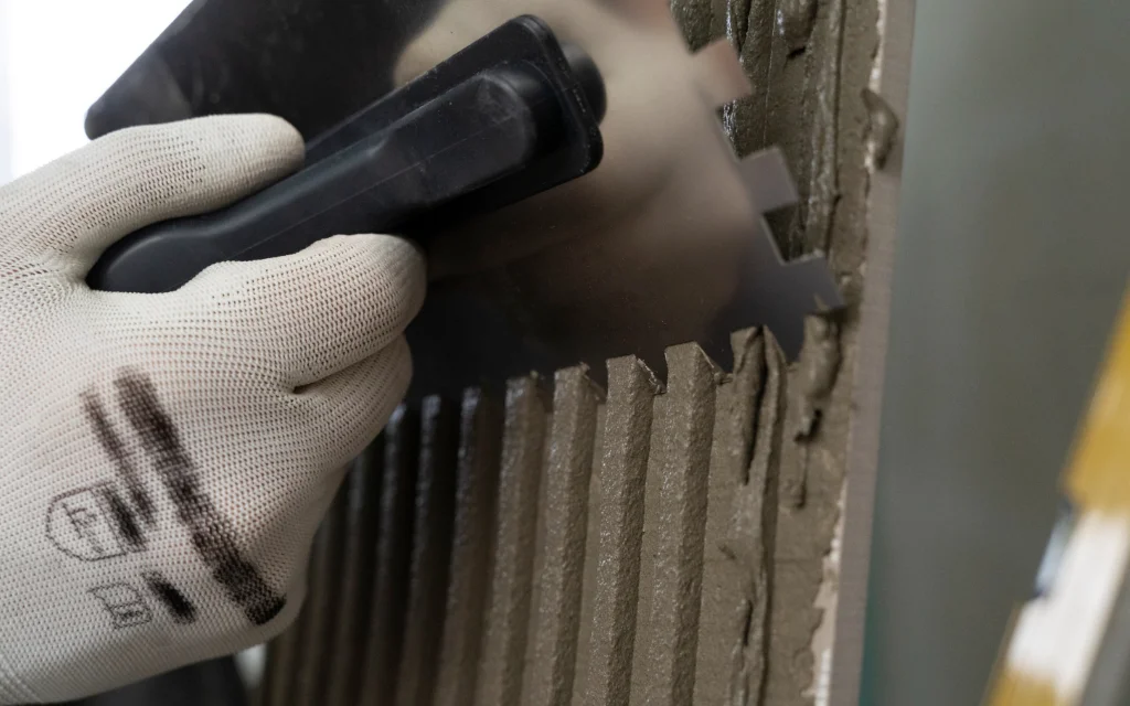 Close-up of a gloved hand gripping a handheld cutting/grinding tool against a metal edge with jagged, torn profiles.