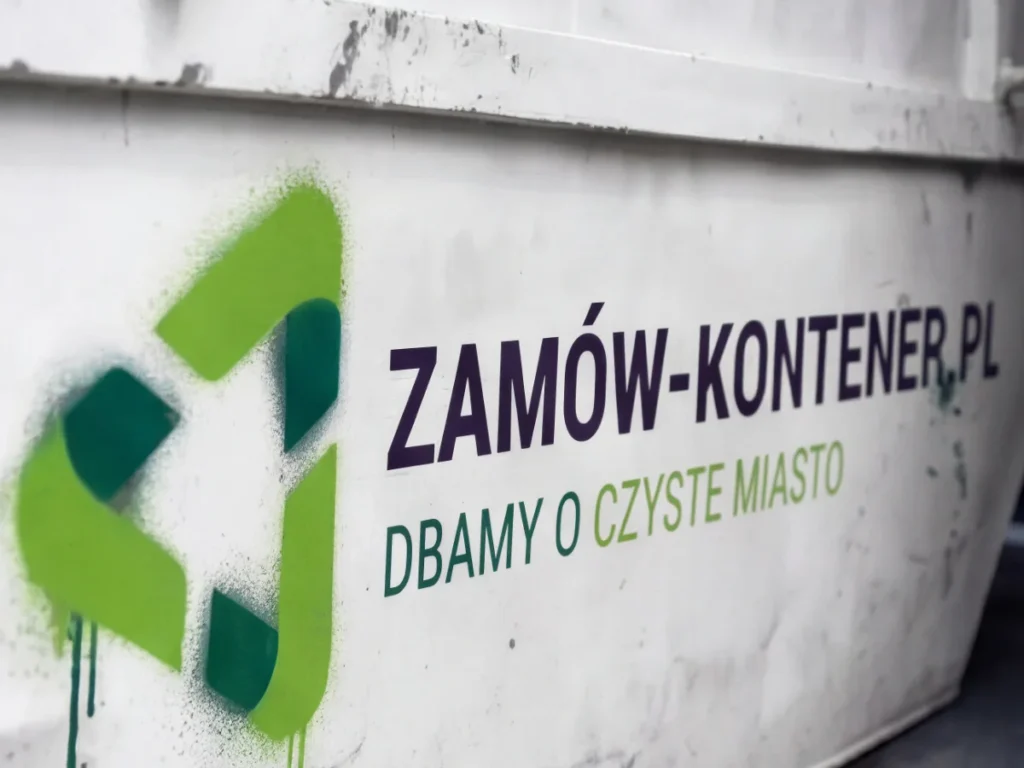 Graffiti on a white dumpster advertising Zamów-Kontener.pl with green logo and slogan “Dbamy o czyste miasto” (We care for a clean city).